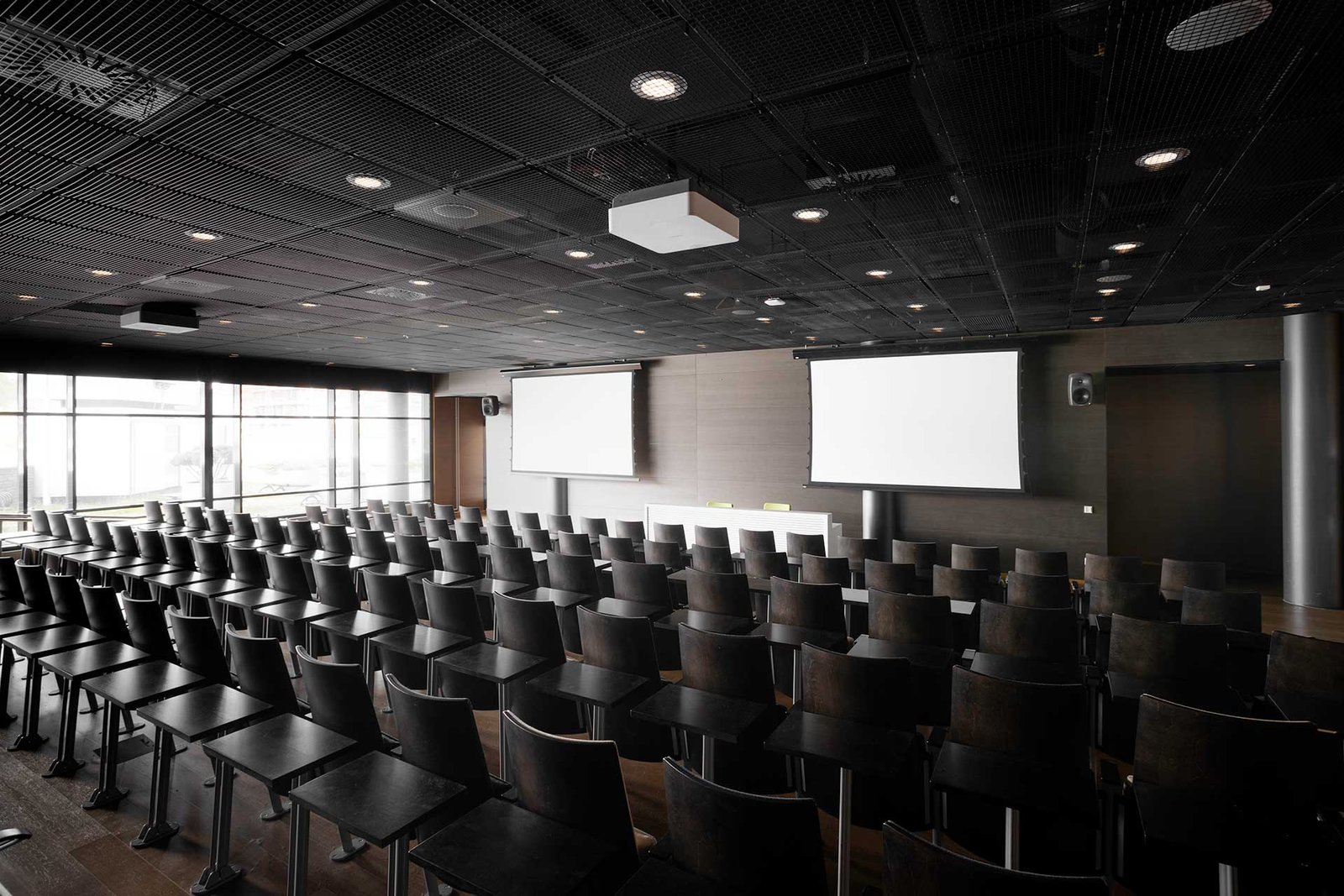 Auditorio, jossa istuinrivit, valkokankaat, projektorit ja kaiuttimet